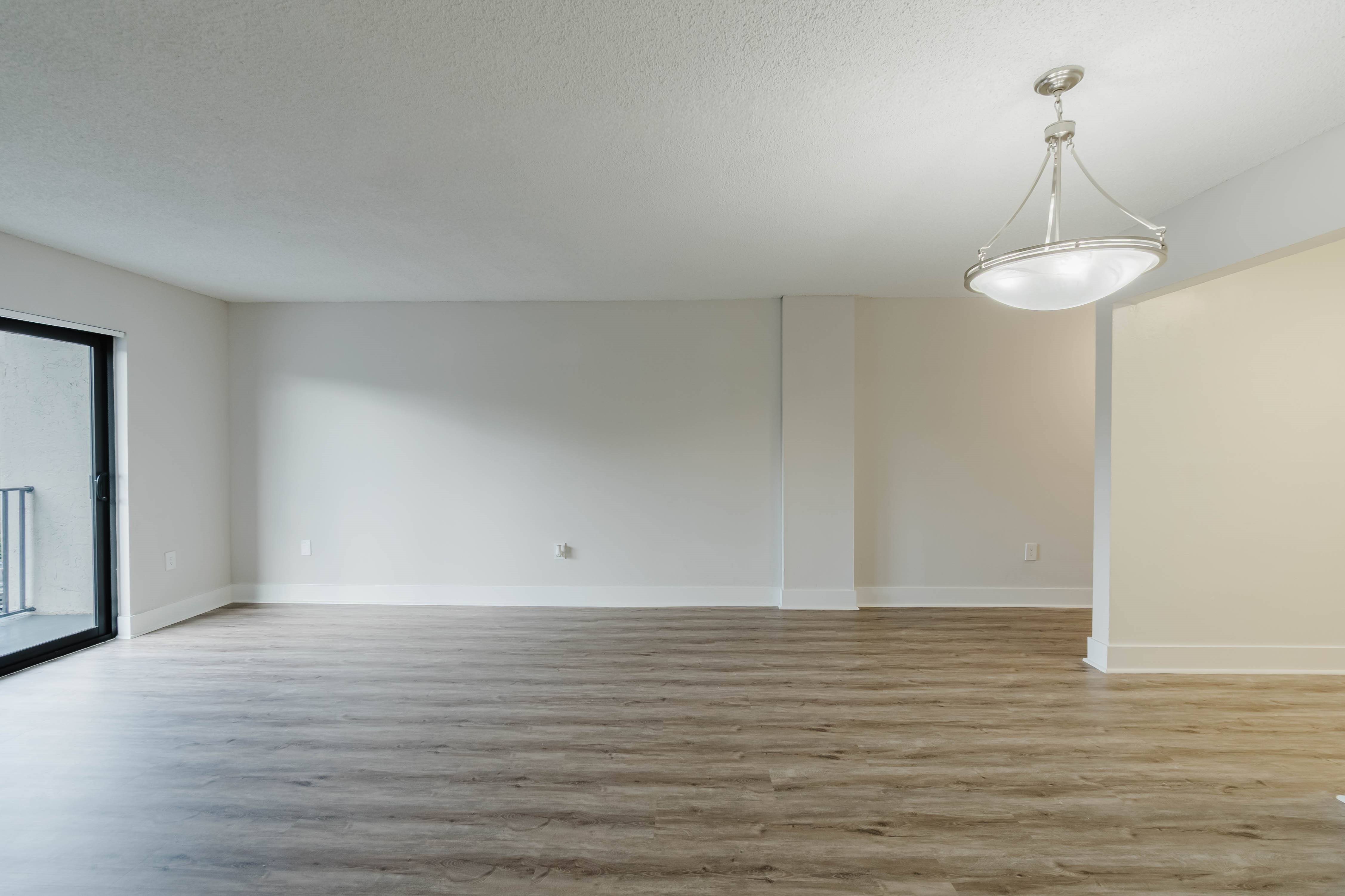 A room with wooden floors and a hanging light fixture.